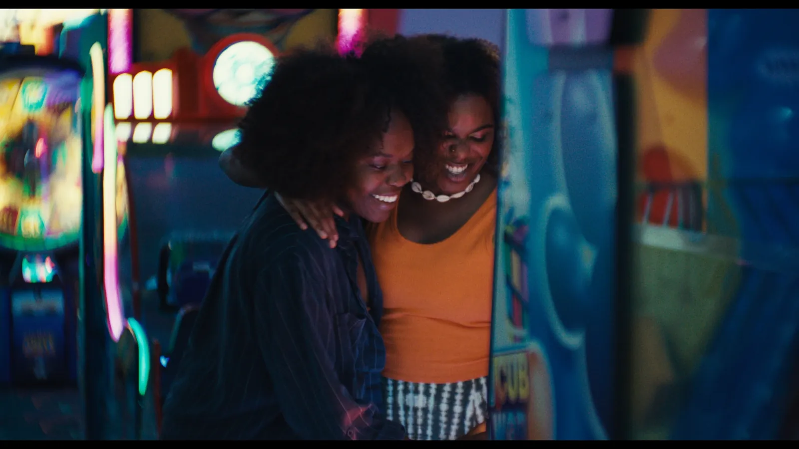 Perfect Love still — two women laughing together at a Coney Island arcade
