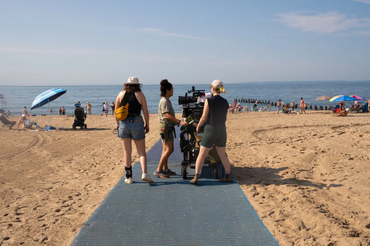 Behind the scenes — crew and cast gathered on the sand by the ocean